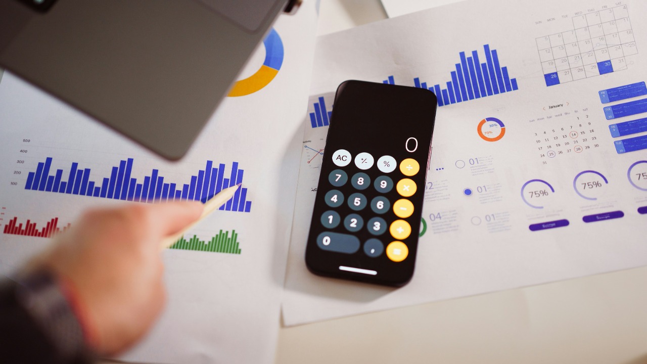 Image Credit: a calculator sitting on top of a table next to a laptop — Jakub Żerdzicki