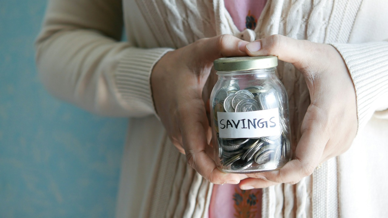 Image Credit: a woman holding a jar with savings written on it — Towfiqu barbhuiya