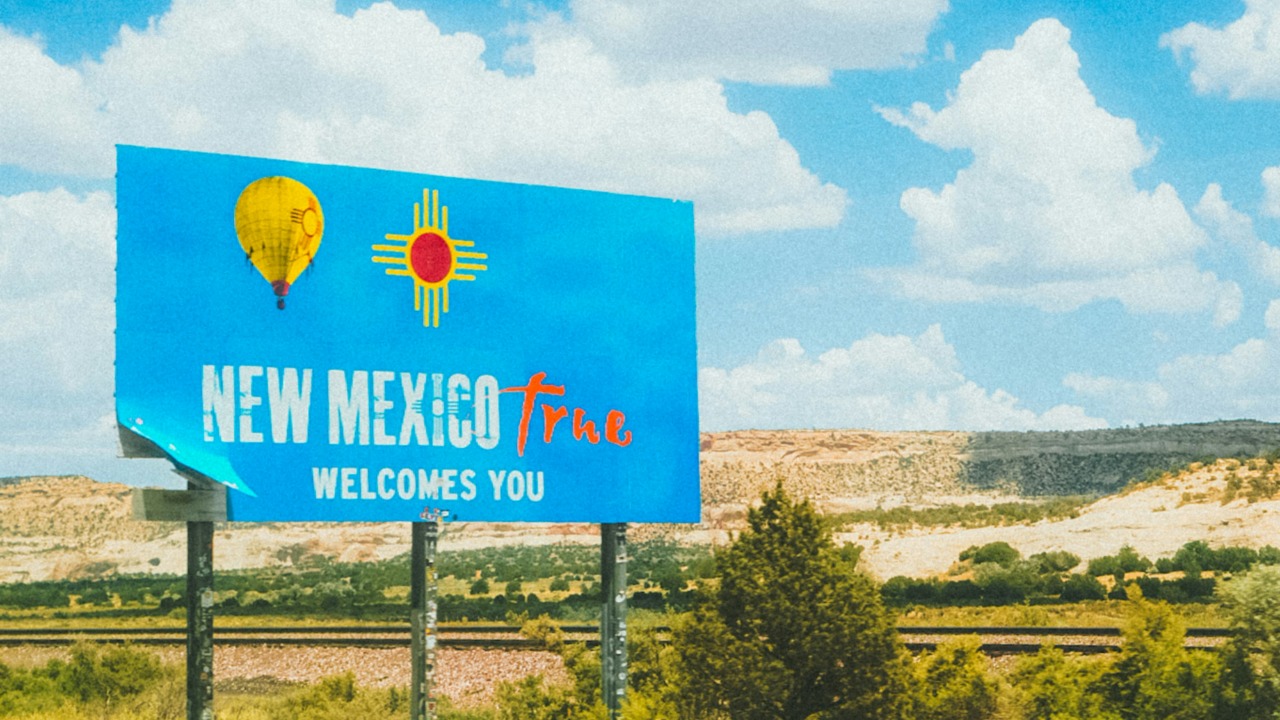 Image Credit: a blue sign that says new mexico plaza welcomes you — Jeffrey Keenan