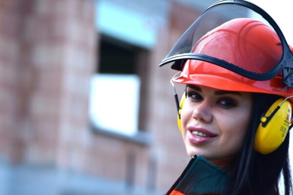 a woman in an orange and green outfit holding a drill — Daniele La Rosa Messina