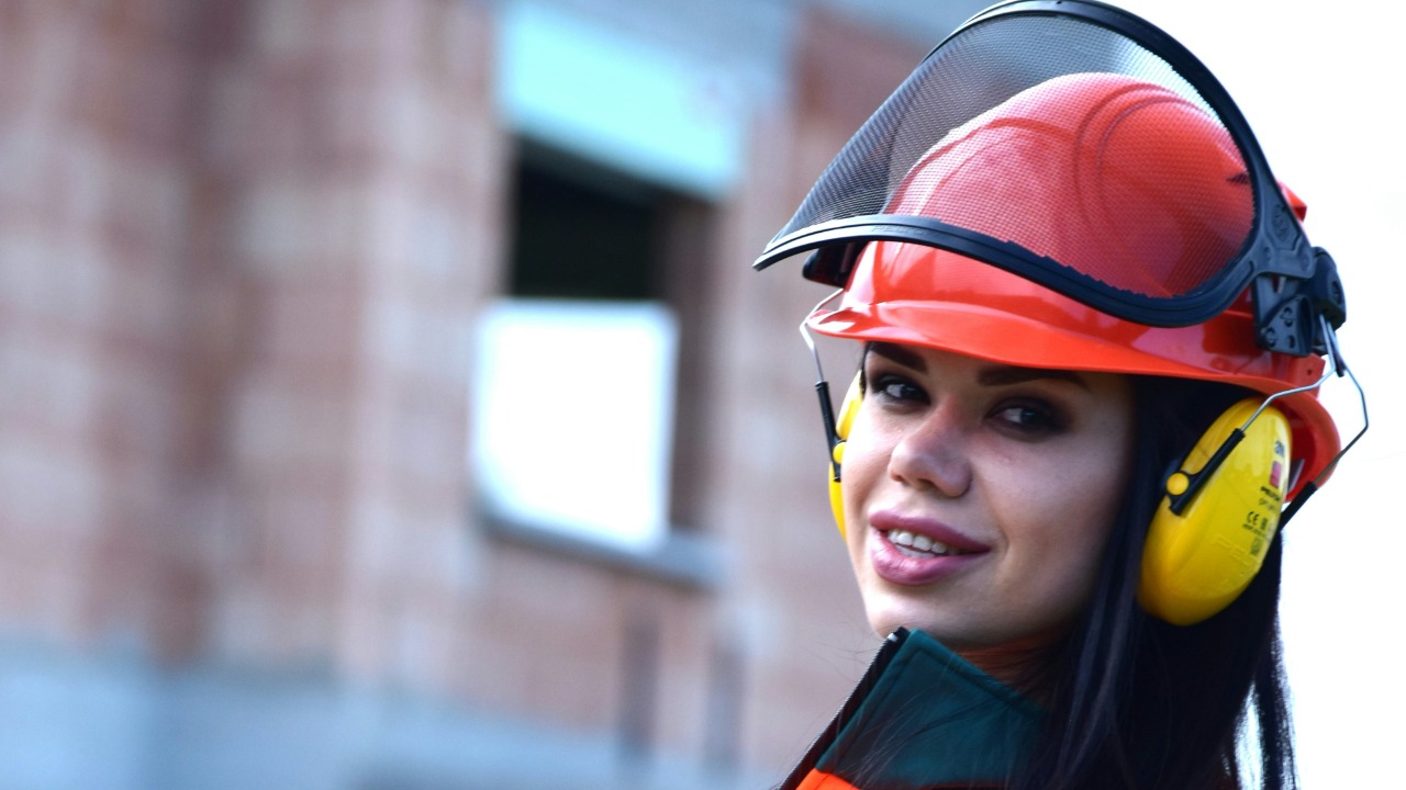 a woman in an orange and green outfit holding a drill — Daniele La Rosa Messina