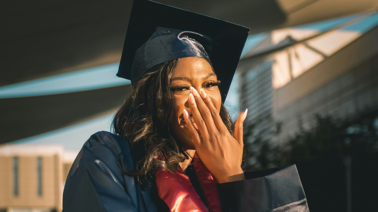 Image Credit: a woman in a graduation gown covers her mouth — Shalom Ejiofor