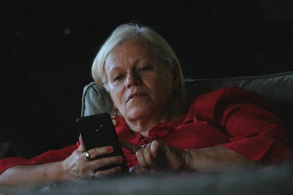 woman in red long sleeve shirt holding black smartphone — Linoleum Creative Collective