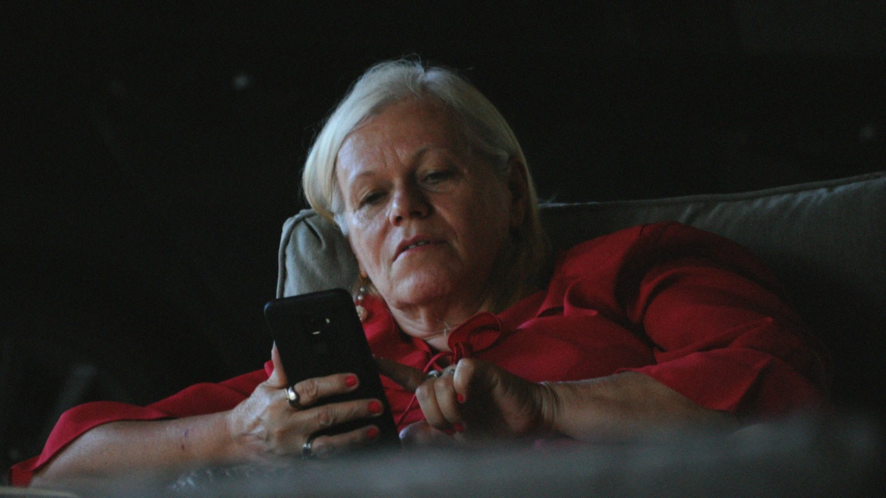 woman in red long sleeve shirt holding black smartphone — Linoleum Creative Collective