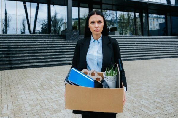 The Struggle of Finding Work After Job Loss An upset woman holds a cardboard box facing the uncertainty of job loss and dismissal
