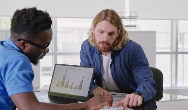 Diverse male startup entrepreneurs discussing company growth looking at graphs and charts