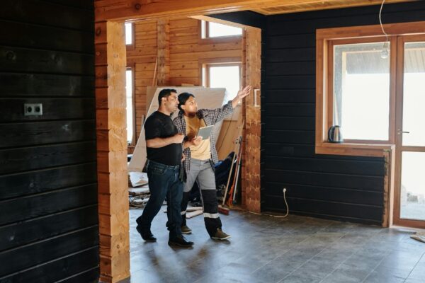 Two adults discussing home renovation in a partially constructed modern wooden interior.