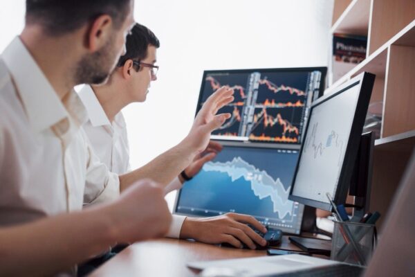 Analyzing data. Close-up of young business team working together in creative office while young woman pointing on the data presented in the chart with pen.