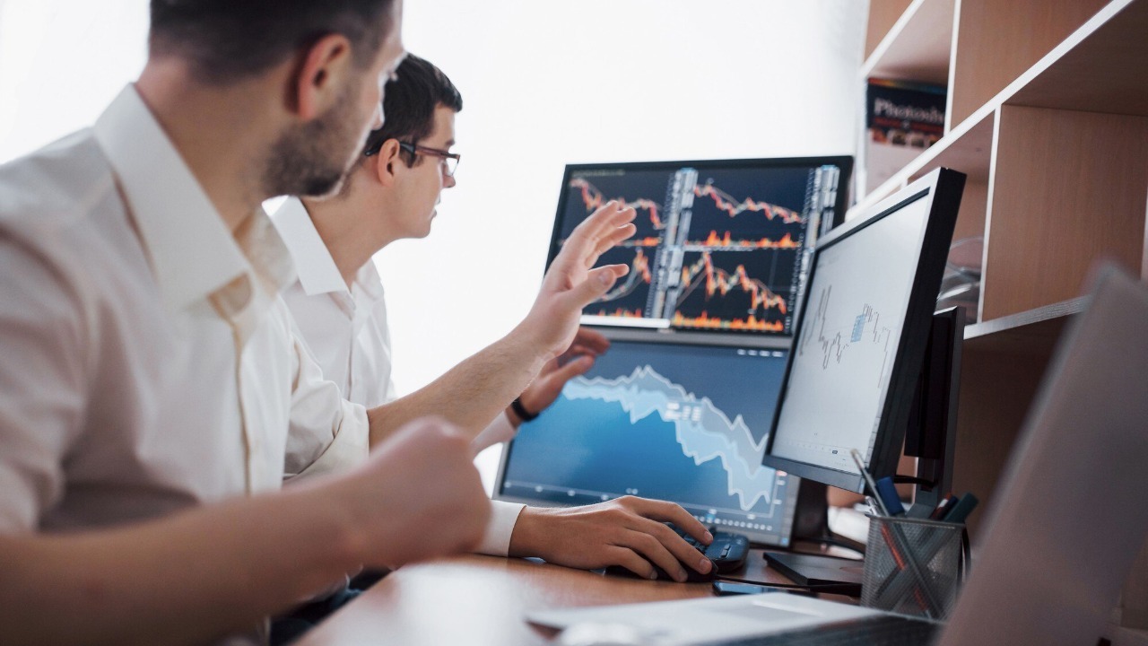 Analyzing data. Close-up of young business team working together in creative office while young woman pointing on the data presented in the chart with pen.
