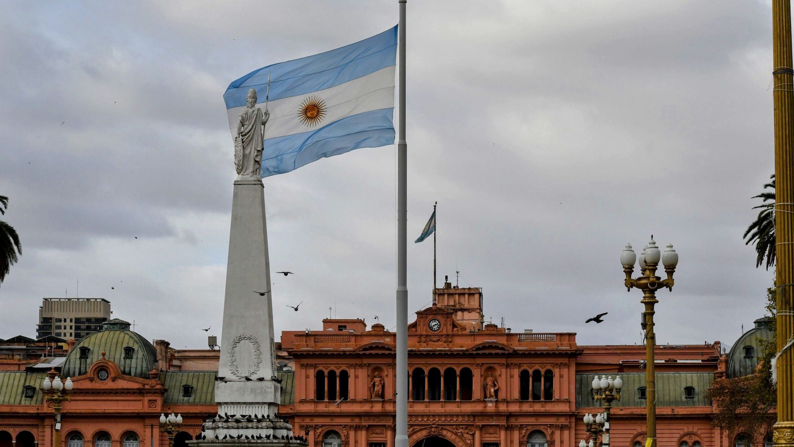 Argentinian flag waving near a prominent building.