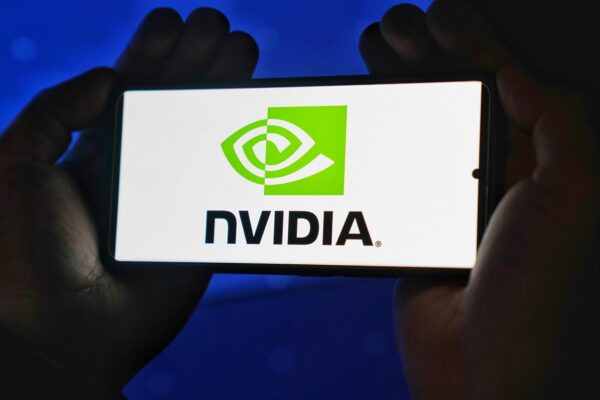 Hands holding a smartphone showing the NVIDIA logo on a bright screen.