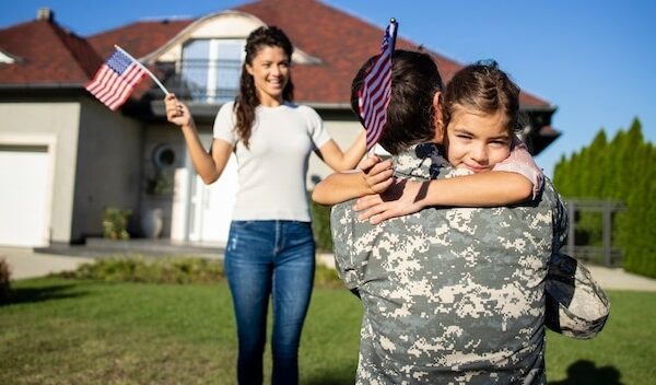 Happy reunion of soldier with his family outdoors in front of their house.