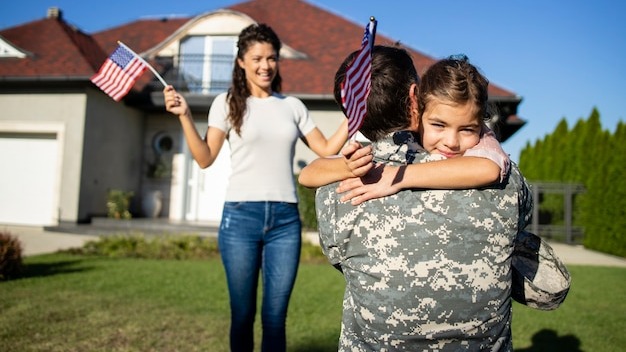 Happy reunion of soldier with his family outdoors in front of their house.