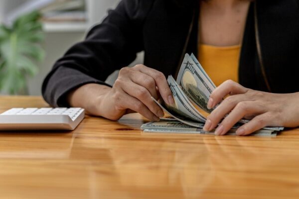 Woman counting dollar bills, she is a cashier serving customers in front of the cashier counter, she counts the money after the service is closed to verify the balance. Conceptual image of money.