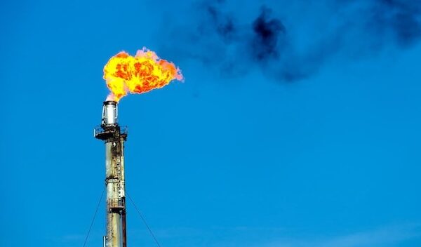 Low angle view of smoke stack emitting fire against sky