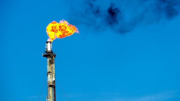 Low angle view of smoke stack emitting fire against sky