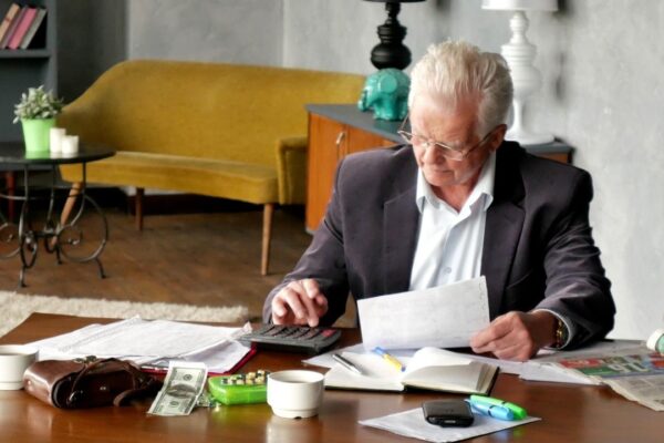 Senior man with papers or bills and calculator at home in evening