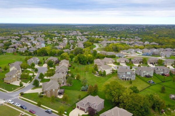 Aerial view of a suburban neighborhood with houses, roads, and lush greenery.