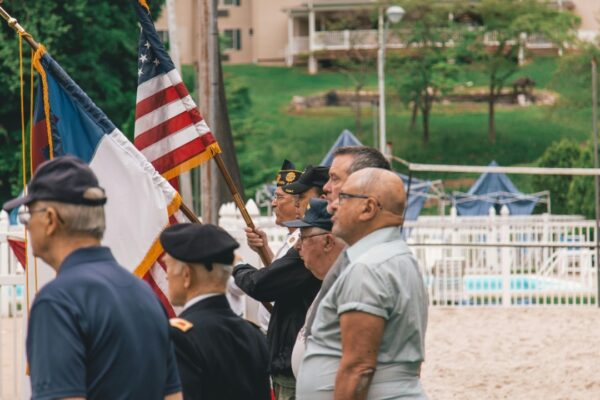 Group of veterans holding flags during an outdoor ceremony showing patriotism.