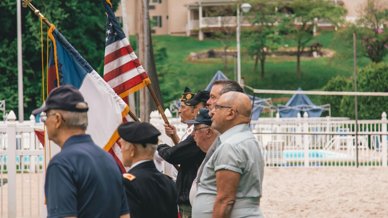 Group of veterans holding flags during an outdoor ceremony showing patriotism.