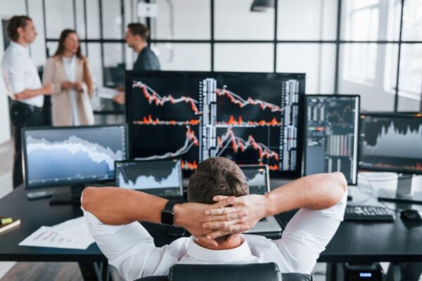 Man sits on chair and takes break Team of stockbrokers works in modern office with many display screens