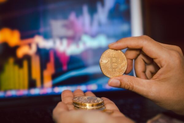 Business men holding bitcoin whit computer trading chart in background