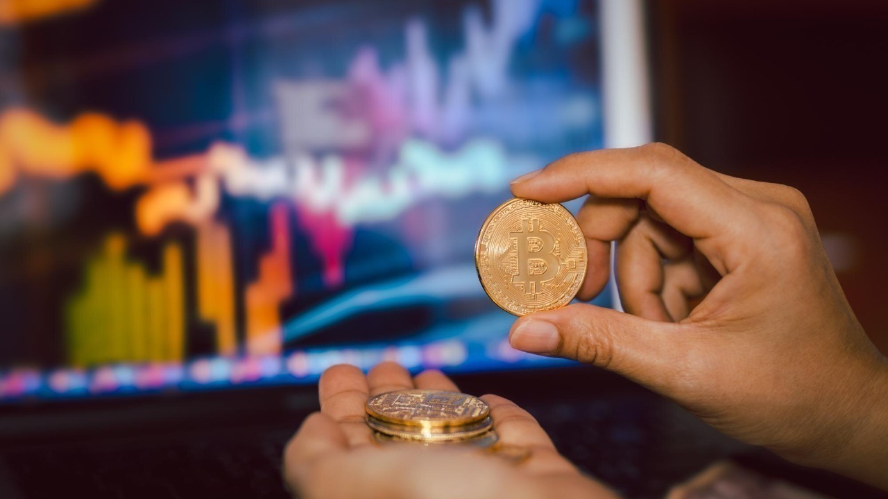 Business men holding bitcoin whit computer trading chart in background