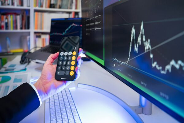 A man holding a remote control in front of a computer