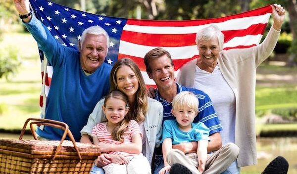 Multi-generation family holding american flag in the park
