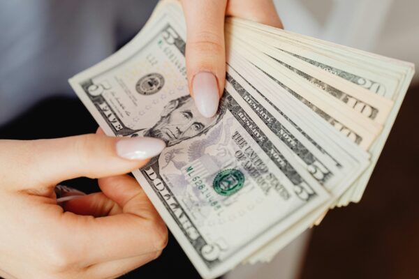 Hands count US dollar bills, showcasing finance and cash handling concepts.