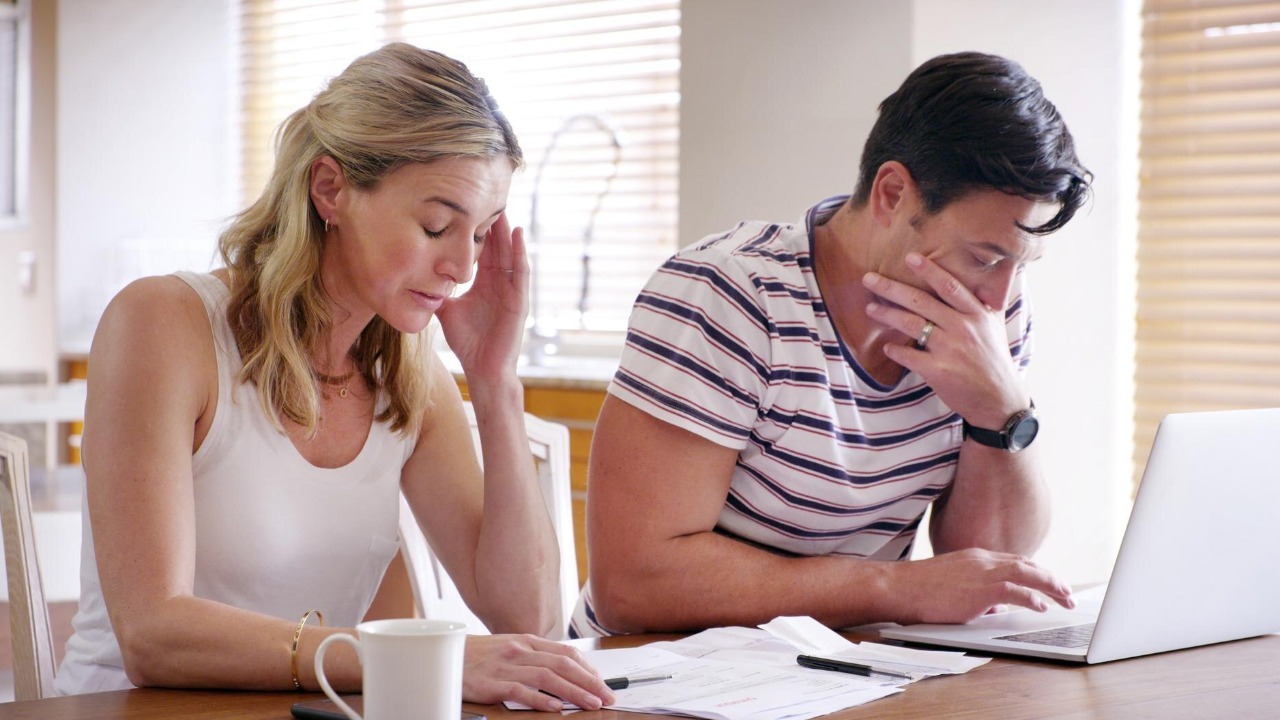 Finance stress and couple with laptop with bills paperwork and online banking issue in debt Home payment due and anxiety from mortgage tax audit or invoice with conversation about savings