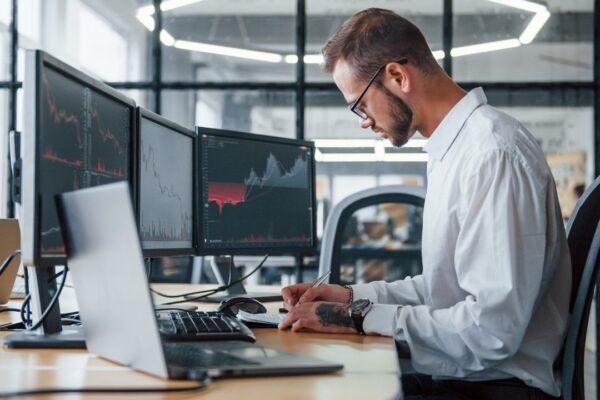 Male stockbroker in formal clothes works in the office with financial market.