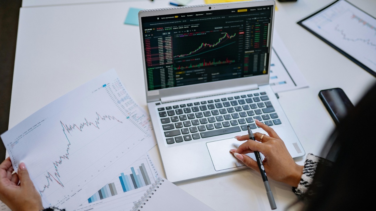 A detailed look at business analysis with a laptop displaying graphs and financial charts on a table.