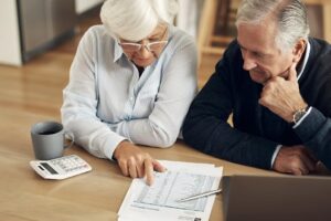 Budget bills and senior couple with paperwork laptop and retirement plan checking finance and tax