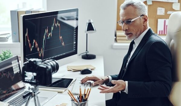 Senior man in elegant business suit using modern technologies while making social media video