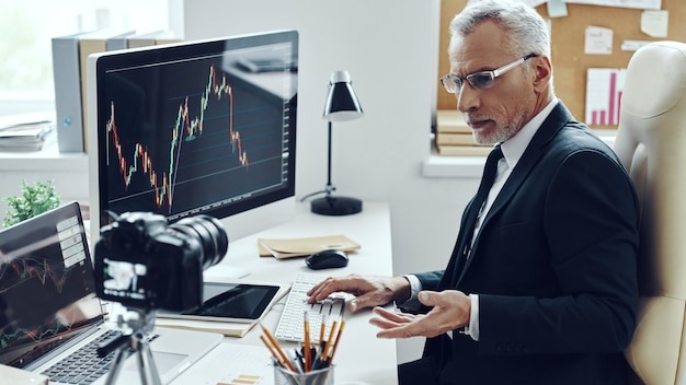 Senior man in elegant business suit using modern technologies while making social media video