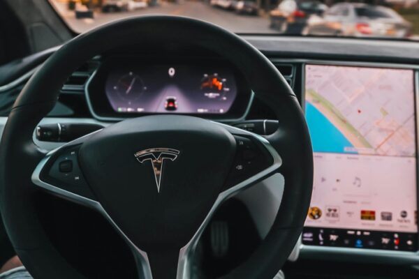 Interior view of a Tesla Model X steering through palm-lined streets of Santa Monica at twilight.
