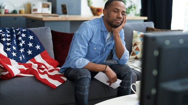 Bored man watching TV with information about election