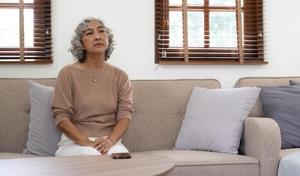 A lonely senior woman is waiting and thinking old memories of her family that will visit her againdepressed elderly people with loneliness and depression sitting alonemissingnostalgiaremembrance