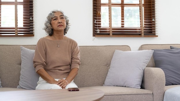 A lonely senior woman is waiting and thinking old memories of her family that will visit her againdepressed elderly people with loneliness and depression sitting alonemissingnostalgiaremembrance
