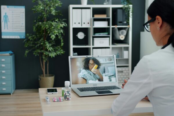 Doctor consulting patient via video call on laptop.
