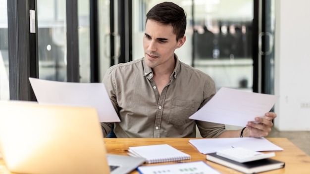 A businessman holding a sales document that the sales department summarizes, he looks displeased when he sees reports of falling sales, he shows signs of stress. Failed sales management concept.