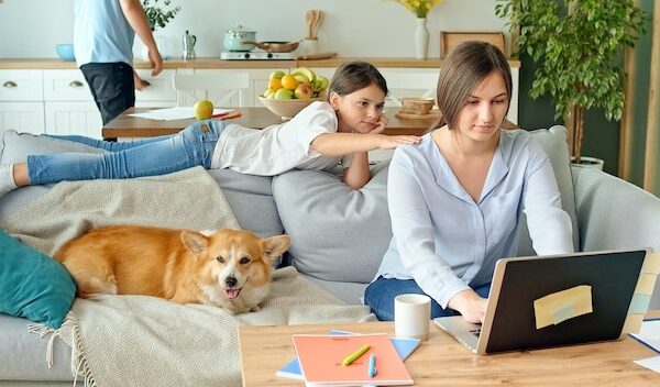 Social distancing a busy mother tries to work remotely with her child and husband at home the daught...