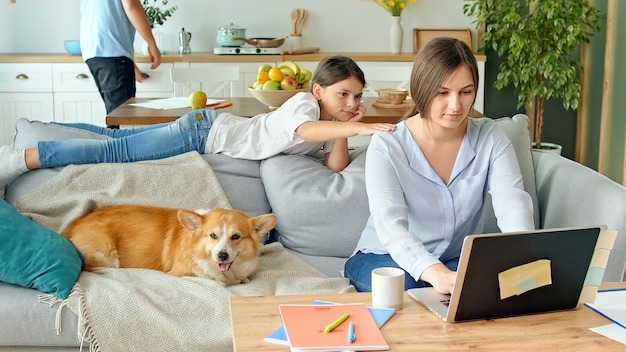 Social distancing a busy mother tries to work remotely with her child and husband at home the daught...
