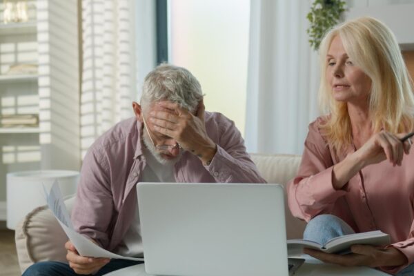 Upset retired mature caucasian woman man couple senior elderly male female arguing worrying laptop
