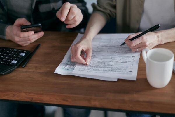 Couple managing finances at home with a calculator, smartphone, and documents.