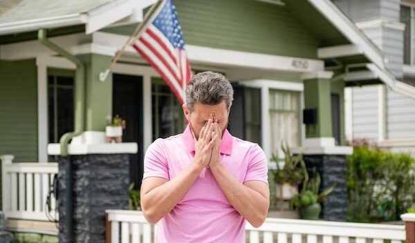 Frustrated bearded man realtor selling or renting house with american flag insurance