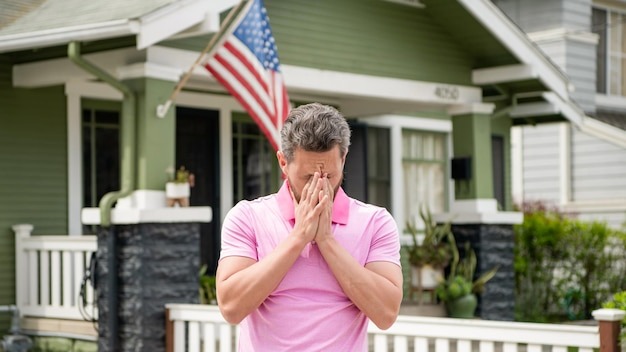 Frustrated bearded man realtor selling or renting house with american flag insurance