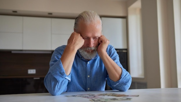 Portrait of bearded senior pensioner male with wrinkled hands counting russian ruble banknotes