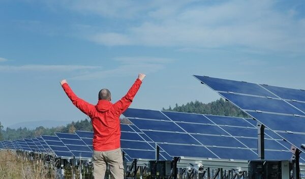 Male engineer at work place, solar panels plant industy in background